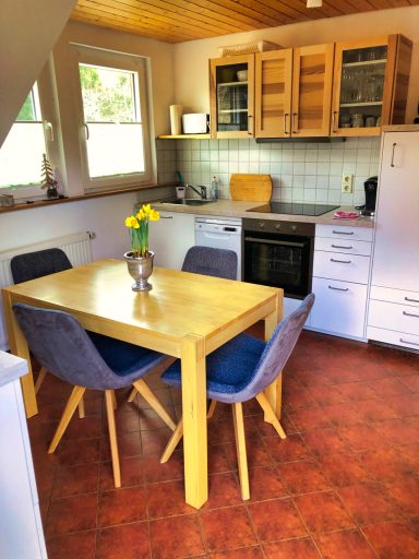 Helle, moderne Küche mit Tisch, Stühlen und Geräten, dekoriert mit einer Blumenvasen.